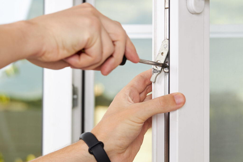 handyman adjusting white pvc plastic window indoors. worker using screwdriver to repair upvc window. homework maintenance Emergency-Locksmiths-Bromley